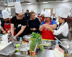 Pokaż zdjęcie: Satyryk Bilguun Ariumbaatar ze swoją drużyną przygotowuje konkursowe danie, przy pracy podpatruje ich prowadząca galę Joanna Brodzik