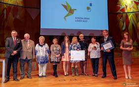 Pokaż zdjęcie: Przedstawiciele PSONI w Koszalinie odbierają nagrodę na scenie