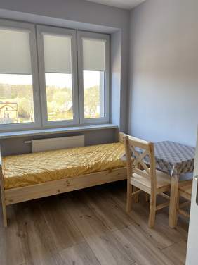 pokój dla podopiecznego domu opieki, łóżko,stojące pod oknem, obok stolik z krzesełkiem