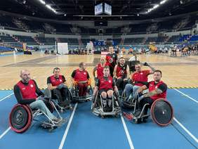 Pokaż zdjęcie: Zawodnicy na specjalnych wózkach do rugby w czerwonych koszulkach