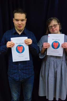 Pokaż zdjęcie: Mężczyzna i kobieta stoją obok siebie w dłoniach przed sobą trzymają dyplomy.