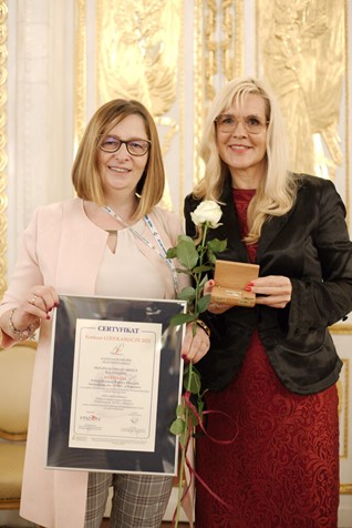 Zdjęcie przedstawia Aleksandrę Włodarskę vel Głowackę i Małgorzata Żbikowska. Jedna z Pań trzyma w dłoniach dyplom informujący o przyznanaj nagrodzie.