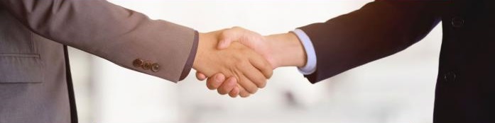 Pokaż zdjęcie: Dwaj mężczyźni w garniturach trzymają dłonie w uścisku.