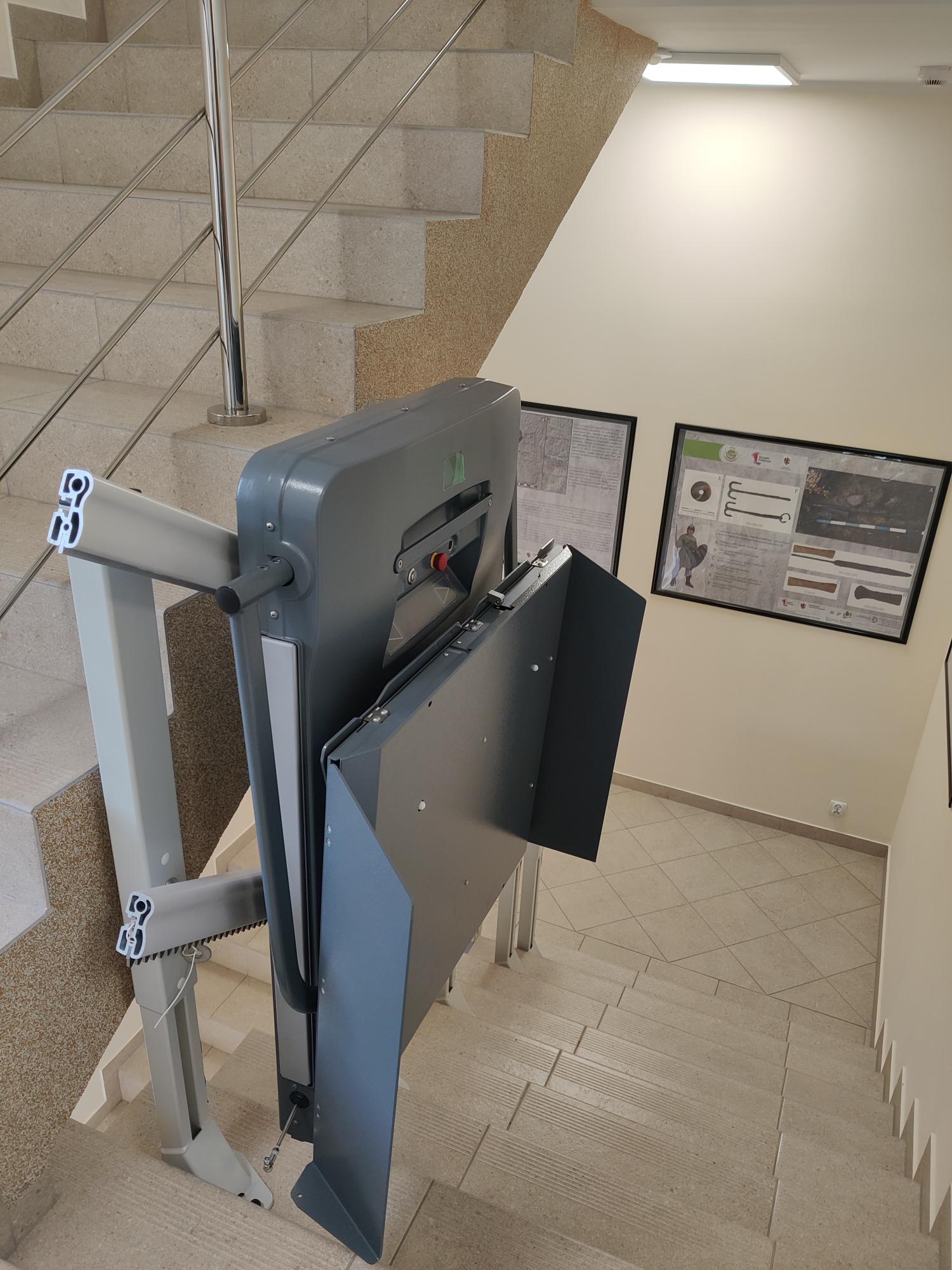 Platforma przyschodowa PPlatforma przyschodowa zamontowana przy poręczy na klatce schodowej.