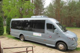 Pokaż zdjęcie: Duży, szary autobus na tle ściany lasu. Na pojeździe widoczne naklejki z logo PFRON oraz START Białystok.