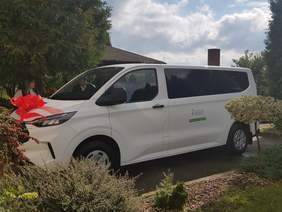 Pokaż zdjęcie: Na zdjęciu bus z czerwoną wstęgą z naklejką ,,DOFINANSOWANO ZE ŚRODKÓW PFRON"