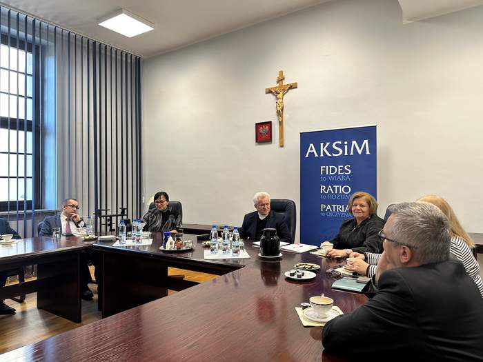 Uczestnicy spotkania siedzą przy stole - przedstawiciele AKSiM i PFRON