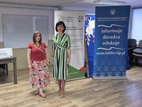 Pokaż zdjęcie: Do pamiątkowej fotografii pozują dwie prelegentki na tle rollupów z logo CIDON oraz Inspekcji Pracy.