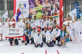 Uczestnicy Igrzysk, na pierwszym planie: drużyna z województwa opolskiego, w tle płonie Pochodnia, po bokach stoją dziewczyny z flagami Olimpiad Specjalnych