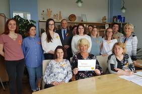 zdjęcie grupowe pracowników oddziału PFRON, 14 osób w tym 2 mężczyzn, mają przypięte pomarańczowe wstążeczki