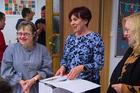 Pokaż zdjęcie: Trzy kobiety uśmiechnięta stoją obok siebie w tle widać trzech mężczyzn.