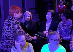 Pokaż zdjęcie: Zdjęcie widowni przed występem artystów, cztery kobiety rozmawiają w luźnej atmosferze.