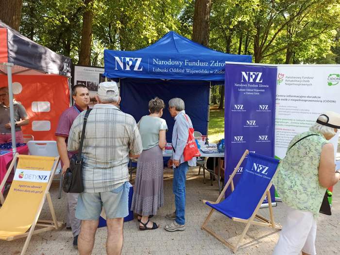 Pokaż zdjęcie: Widoczne namioty w parku, sporo ludzi na zdjęciach, ubranych zwyczajnie, jeden z namiotów jest czerwony, a drugi niebieski