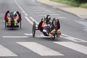 Pokaż zdjęcie: Dwaj mężczyźni podczas wyścigu leżą na rowerach,poruszają się na nich kręcąc rękami,fot.Lublin 112