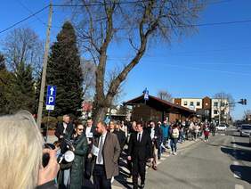 Pokaż zdjęcie: Ulicą Zgierza idzie tłum osób. Ludzie rozmawiają ze sobą. Niektórzy mają na sobie niebieski ubrania. Jest piękna pogoda. 