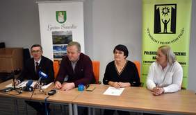 Pokaż zdjęcie: przy stole siedzią dwaj mężczyźni i dwie kobiety, udzielają wywiadu.