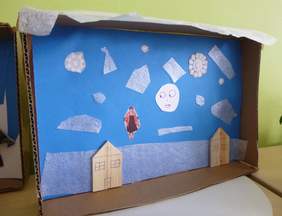 Pokaż zdjęcie: Warsztaty artystyczne w SP nr 34 w Krakowie. Na zdjęciu papierowa makieta - domy i kobieta na niebieskim tle.