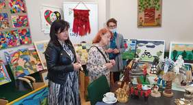 Pokaż zdjęcie: Przewodnicząca oraz członkowie Komisji oceniają prace zgłoszone w kategorii "Rzeźba kameralna i płaskorzeźba". Prace wyeksponowane są na stole 