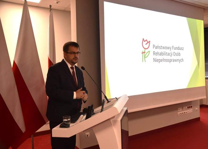 Pokaż zdjęcie: Dyrektor Oddziału Lubuskiego PFRON Andrzej Gonia w trakcie przemówienia, na tle prezentacij z logo PFRON, na sali jest dużo osób