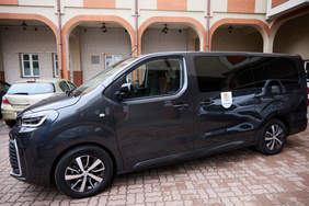 Pokaż zdjęcie: Dziewięciomiejscowy mikrobus dla DPS w Łomży zaparkowany przed budynkiem placówki.