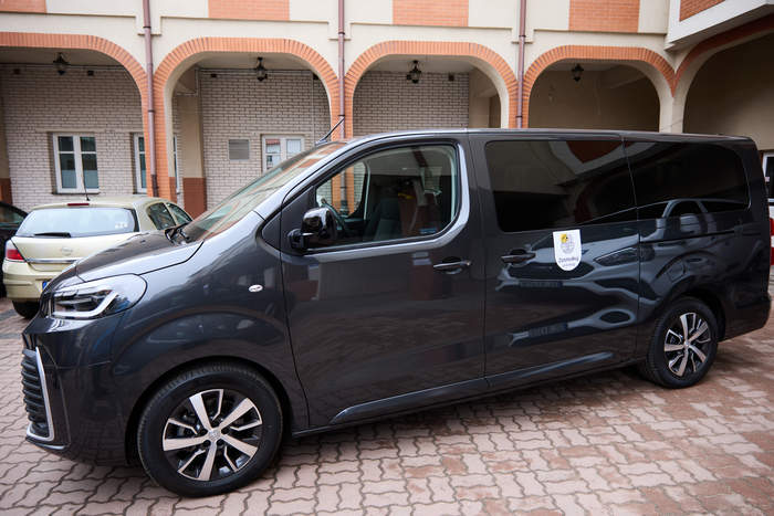 Pokaż zdjęcie: Dziewięciomiejscowy mikrobus dla DPS w Łomży zaparkowany przed budynkiem placówki.