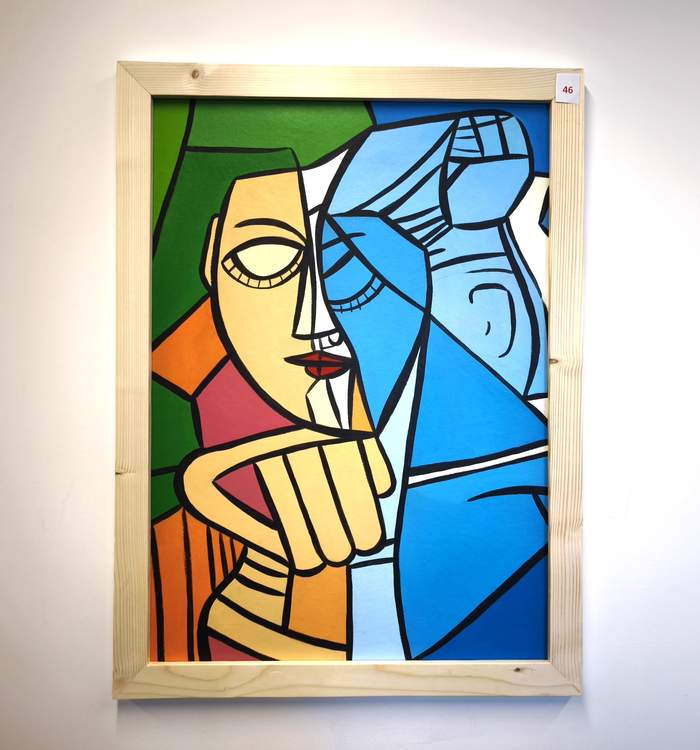 Pokaż zdjęcie: Obraz w orientacji pionowej, w jasnej, drewnianej ramie, przedstawiający portret w stylu kubistycznym. Twarz i postać są zgeometryzowane, podzielone na ostre, kolorowe płaszczyzny: żółte, pomarańczowe, zielone, czerwone, jasnoniebieskie i ciemnoniebieskie. W centrum znajduje się fragment twarzy o szeroko otwartych oczach i małych czerwonych ustach, z zaciśniętą dłonią pod brodą.