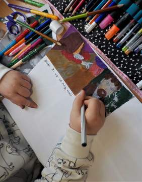 Pokaż zdjęcie: Warsztaty artystyczne w SP w Wielkiej Wsi. Na zdjęciu dłonie dziecka. Dziecko tworzy komiks używając do tego pisaków i reprodukcji prac Wyspiańskiego