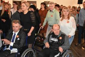 Uczestnicy balu podczas zabawy - na pierwszym planie widać dwóch mężczyzn na wózkach inwalidzkich, które trzymają kobiety