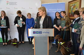 Pokaż zdjęcie: Osoba przy mównicy, w tel osoby słuchające. 