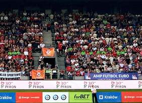 Pokaż zdjęcie: Trybuny wypełnione kibicami. Przy boisku widoczny logotyp PFRON 