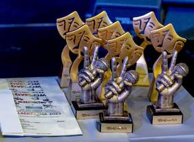 Pokaż zdjęcie: na stole stoją statuetki dla uczestników festiwalu oraz dyplomy 