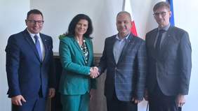 Pokaż zdjęcie: Grupa osób - jedna kobieta i trzech mężczyzn pozują do zdjęcia. Wszyscy są elegancko ubrani i uśmiechnięci. 