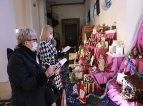 Pokaż zdjęcie: miejsce kościół w którym rozmieszczono prace konkursowe tj. szopki Bożonarodzeniowe, dwie osoby stoją i oceniają prace 