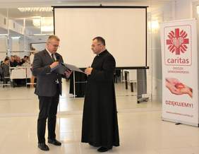 Pokaż zdjęcie: Ksiądz Bogusław Pitucha Dyrektor Caritas Diecezji Sandomierskiej odbiera pamiątkowy grawerton wręczany przez Jerzego Dębskiego Dyrektora Oddziału Lubelskiego PFRON