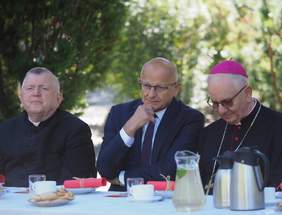 Pokaż zdjęcie: Zdjęcie trzech mężczyzn siedzących przy stole, od lewej siedzi ksiądz prałat, pośrodku prezydent miasta Lublin, po prawej arcybiskup 