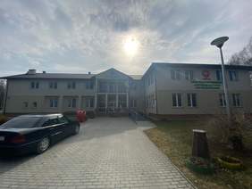 budynki ZAZ, nad nimi słońce, przed stoi auto