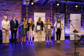 Pokaż zdjęcie: Na scenie stoi osiem osób, pozują do pamiątkowego zdjęcia.