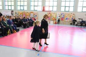 Dyrektor Aleksandra Gierej idzie w stronę sceny i trzyma za rękę dziewczynkę