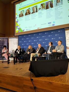 Pokaż zdjęcie: Panel dyskusyjny, w fotelach siedzi sześć osób, od lewej trzy kobiety oraz trzech mężczyzn.