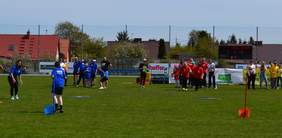 Pokaż zdjęcie: Na zdjęciu kilkanaście osób na boisku. 3 z nich biegną