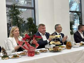 Pokaż zdjęcie: Zdjęcie stołu przy którym siedzą zaproszeni goście.