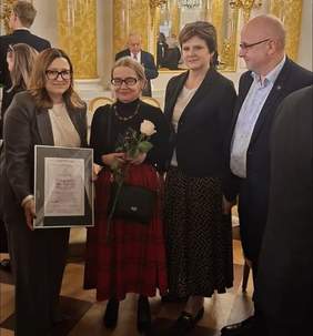 Pokaż zdjęcie: Trzy kobiety i mężczyzna pozują z laureatką lodołamacza. Kobieta z lewej trzyma dyplom w ręku. Laureata stoi obok z różą w ręku.