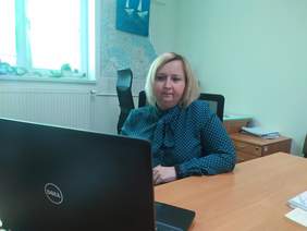 Pokaż zdjęcie: Kobieta siedzi przy biurku na którym stoi otwarty laptop