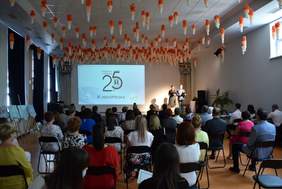 Pokaż zdjęcie: Jubileusz 25-lecia PSONI Koło w Wolbromiu. Sala pełna zaproszonych gości. Na końcu sali widać scenę i napis "25 lat"
