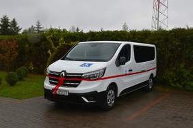 Pokaż zdjęcie: Biały bus udekorowany czerwoną wstęgą. Na busie naklejki z logo PFRON i osoby na wózku.