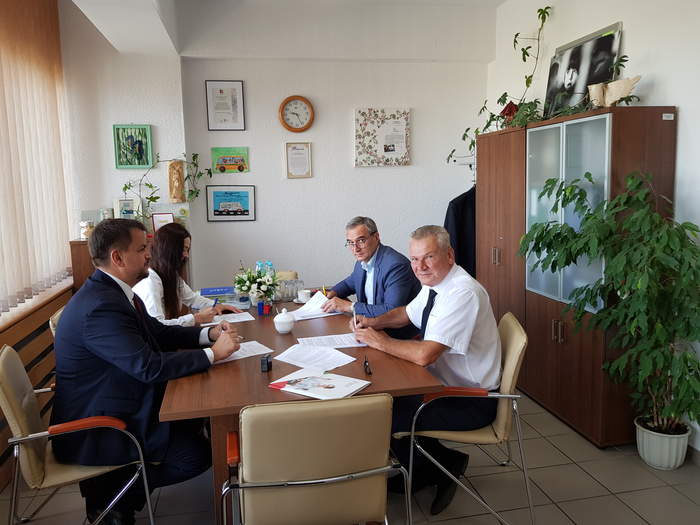 Pokaż zdjęcie: Przy stoliku umowę podpisują Dyrektor Oddziału Lubuskiego PFRON oraz Przedstawiciele Powiatu Zielonogórskiego, wszyscy trzymają w ręku długopisu, niektórzy patrzą w obiektyw