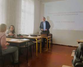 Pracownik Kujawsko-Pomorskiego Oddziału PFRON - Piotr Kopyciński - podczas prelekcji, w tle ekran, a na nim wyświetlony slajd z prezentacji