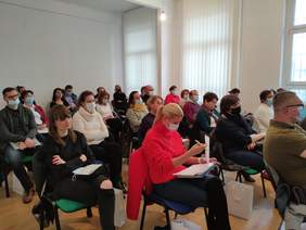 Pokaż zdjęcie: Fragment sali, odprzodu siedzący uczestnicy. 