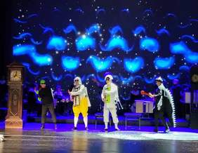 Pokaż zdjęcie: Jedna ze scen spektaklu. Czterech kolorowo ubranych aktorów na scenie w trakcie tańca