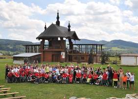 Pokaż zdjęcie: Duża grupa osób pozuje do zdjęcia pod drewnianym ołtarzem